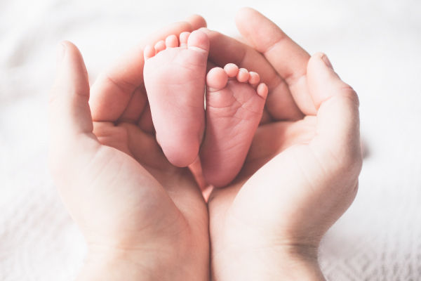 赤ちゃんの小さな足を包む母親の両手